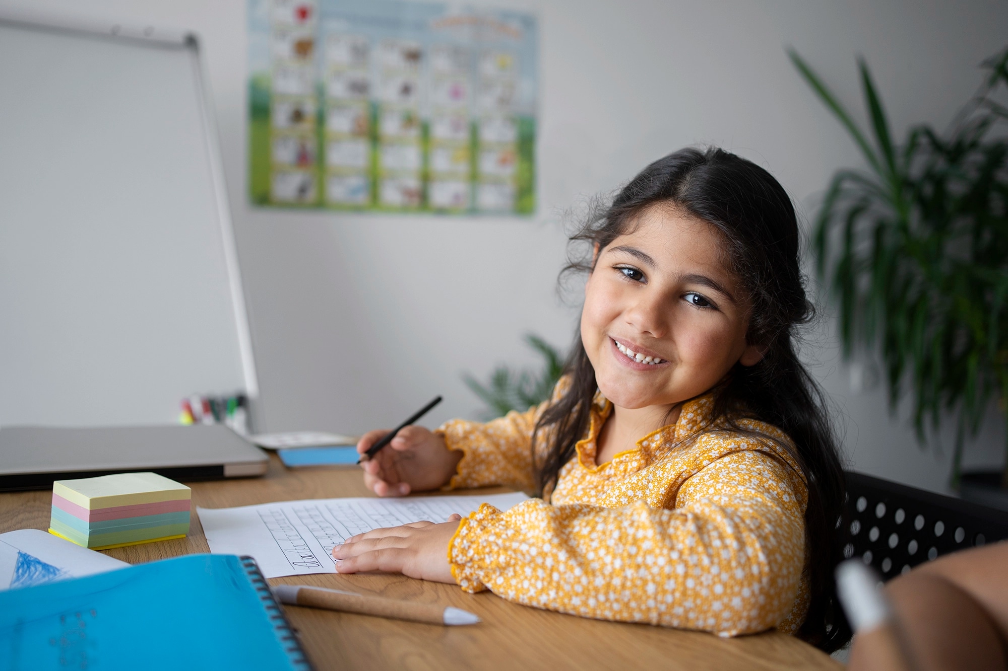 A smiling girl drawing at her desk